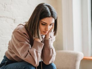 Person sitting alone and looking down while feeling distressed